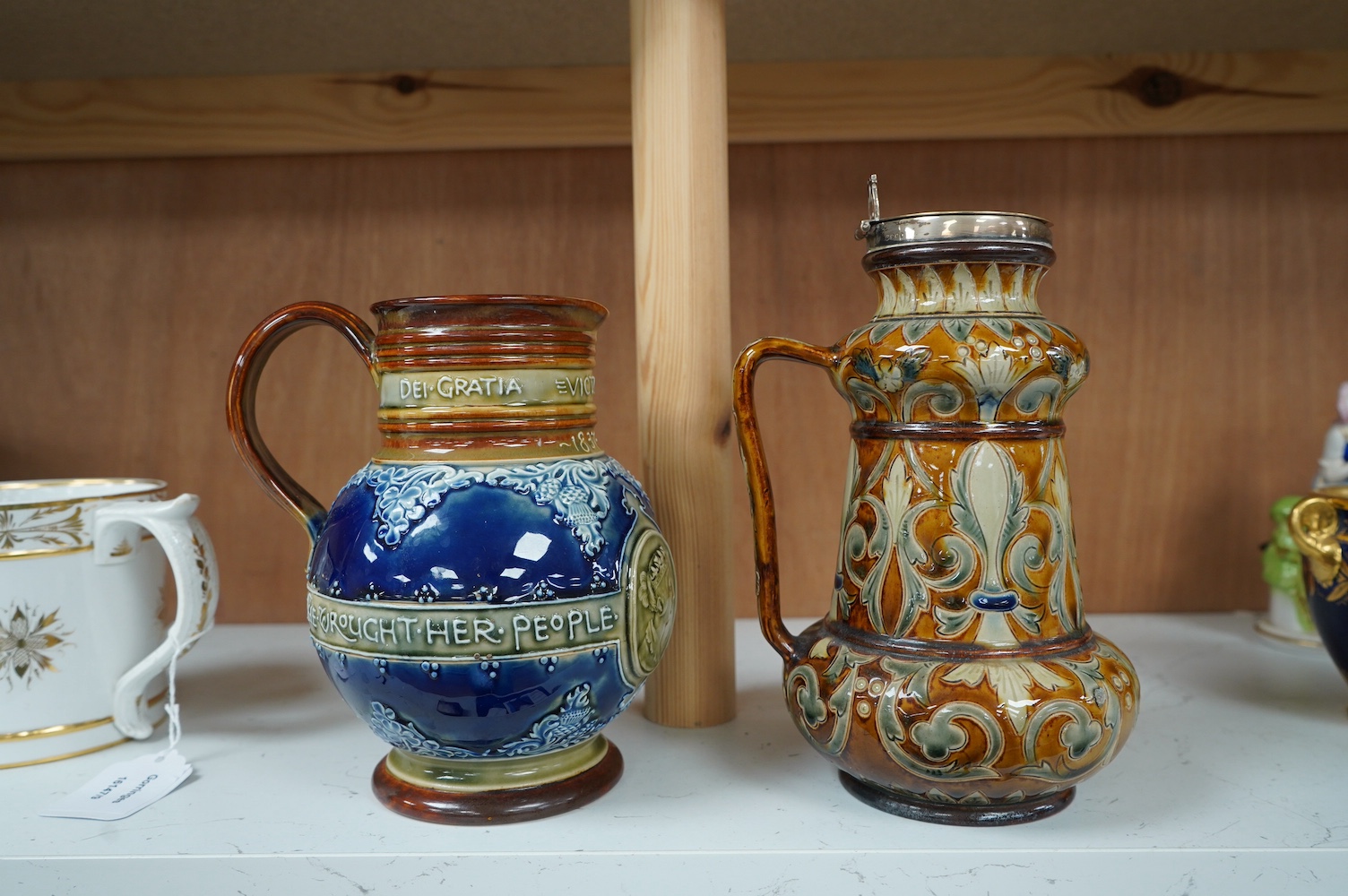 A Doulton Lambeth silver mounted stoneware jug, the silver mount, London 1891, and a Doulton Lambeth Queen Victoria Diamond Jubilee jug, silver mounted jug 21cm high (2). Condition - silver mounting dented